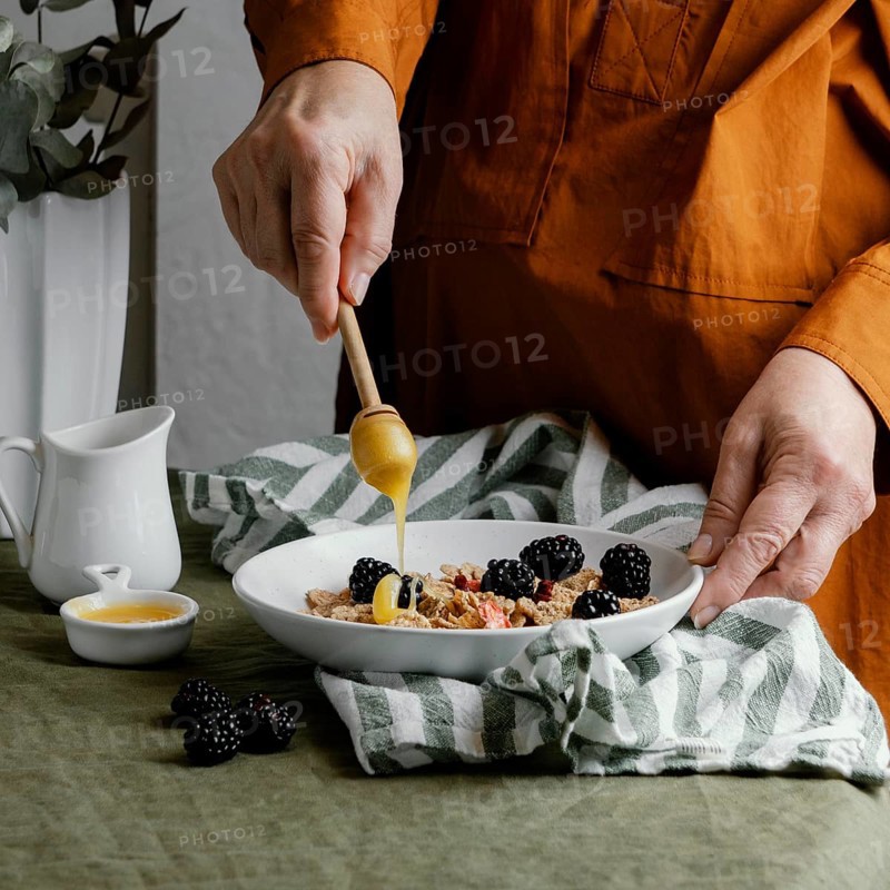 Close up hand pouring honey cereals