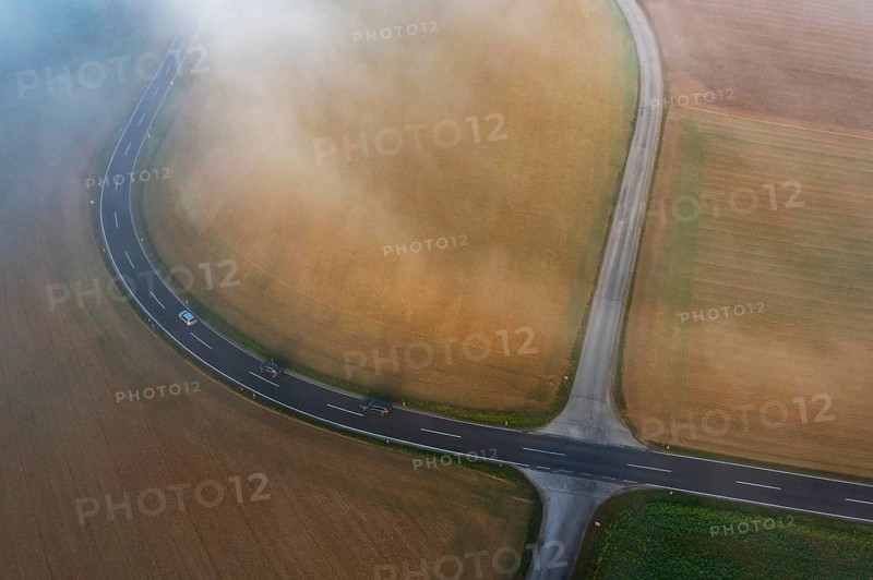 Drone view of a rural landscape shrouded in dense morning fog with a road junction near Prambachkirchen