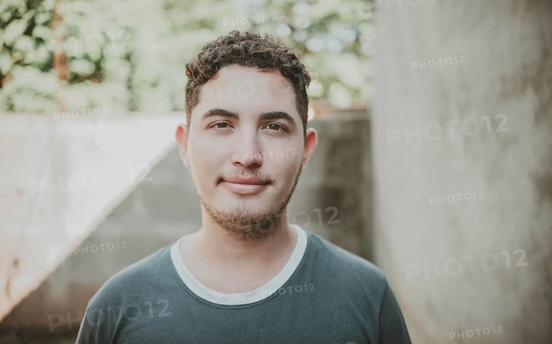 Portrait of cheerful young latin guy smiling at camera outdoors. Portrait of Latin American man looking and smiling at the camera