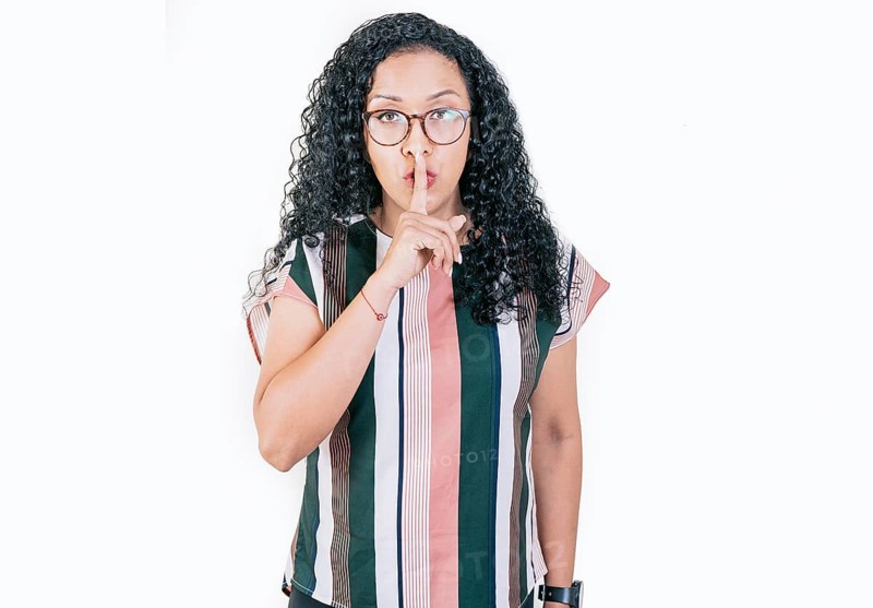 Young woman shushing you with her finger. Afro woman making silence gesture isolated