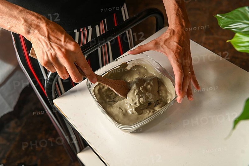 Masseuse preparing mixing clay and water for anti inflammatory massage in spa center