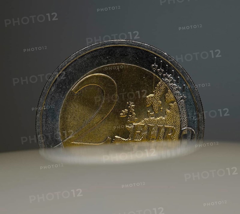 A 2-euro coin as a macro shot in the slot of a piggy bank
