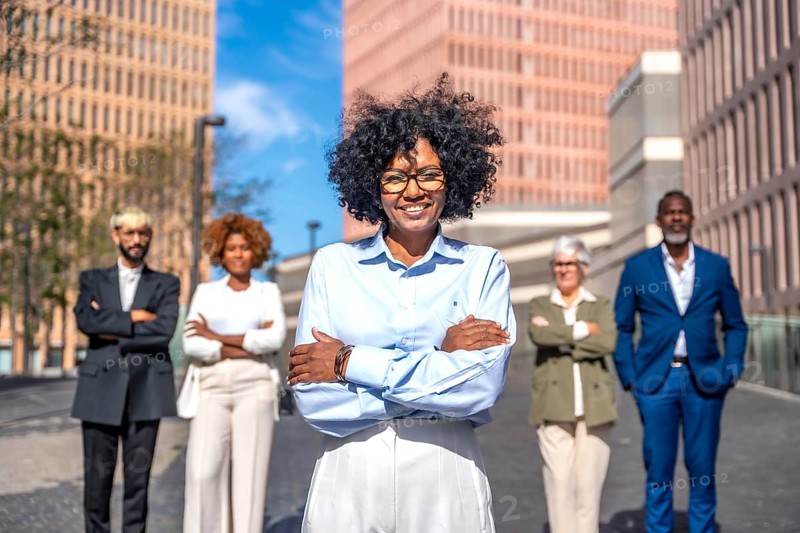 Frontal portrait of a happy entrepreneur standing proud next to her team in the city street