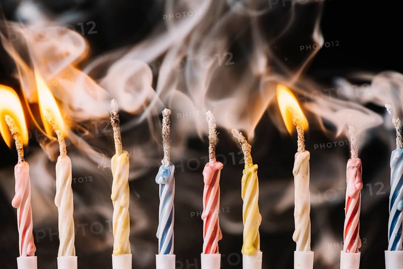 Burning extinguished candle against black background