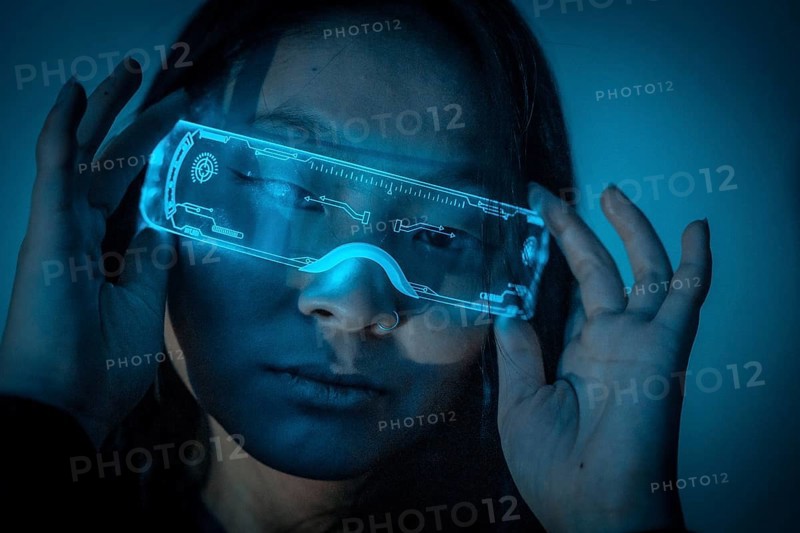 Studio photo with blue background with neon lights of a beautiful young chinese woman wearing futuristic glasses
