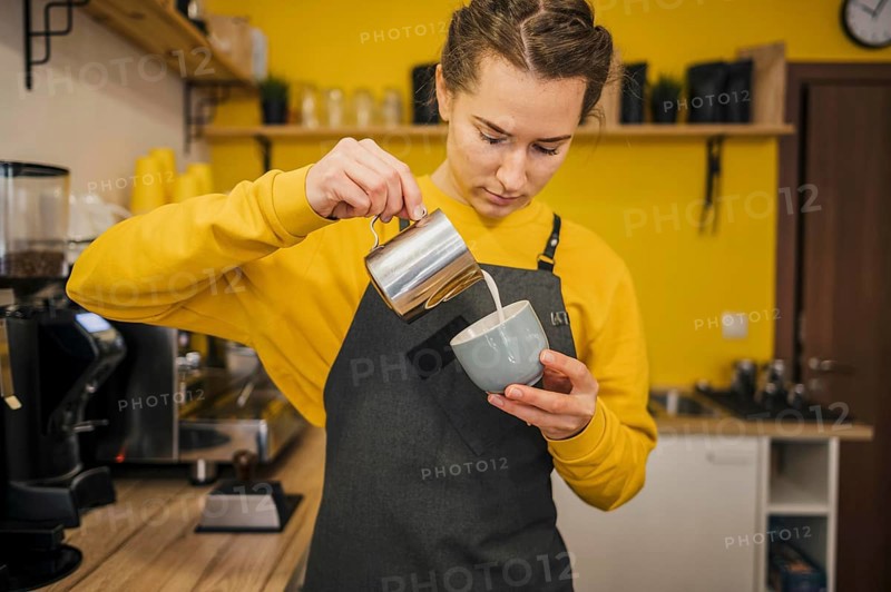 Front view barista pouring milk coffee