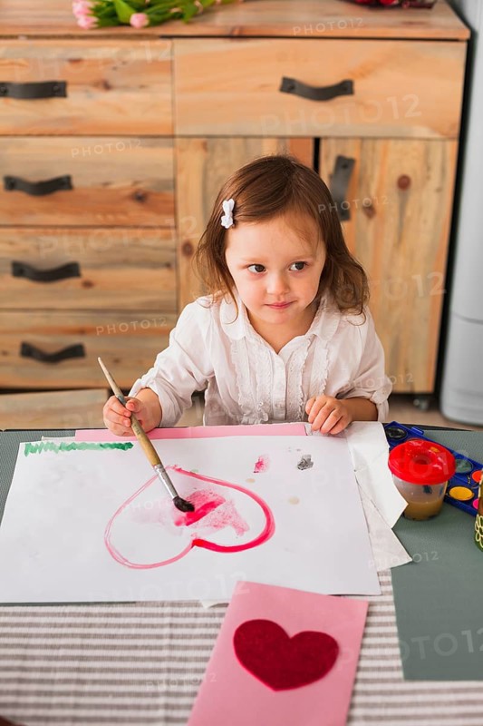 Little girl painting heart paper