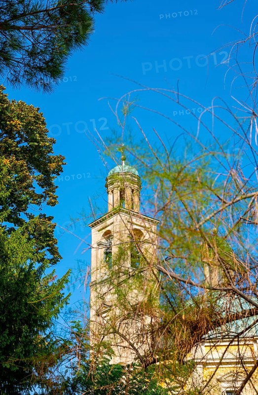 Temple of the Holy Cross with Tower Against Blue Clear Sky and Tree Branch in a Sunny Day in Riva San Vitale