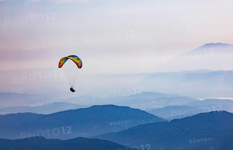 Paragliders high above the mountains with a view of the Klagenfurt basin and the Karawanken