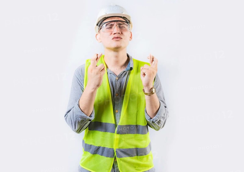 Portrait of young engineer making a wish. Handsome engineer crossing fingers making a wish