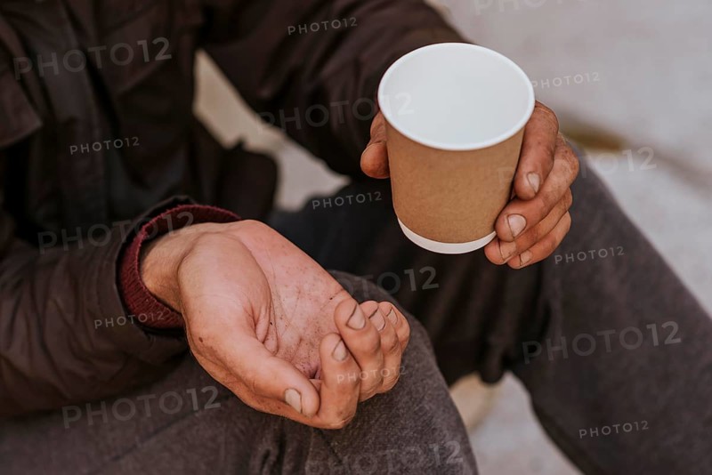 Homeless man holding hand out help empty cup