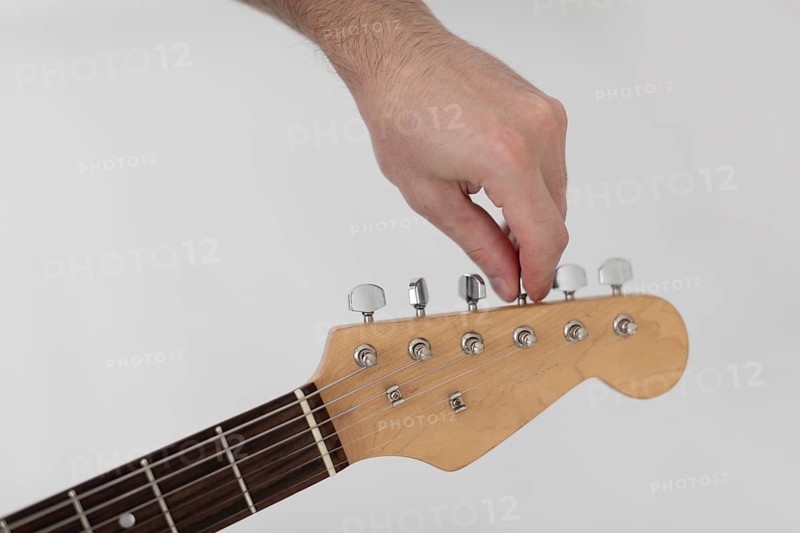 Male musician tuning electric guitar
