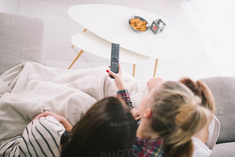 Girlfriends watching tv cuddling sofa