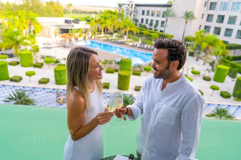 Newlywed couple toasting with champagne standing on the terrace of a luxury hotel
