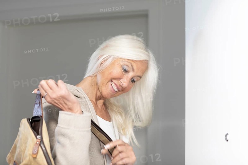 Elderly woman with long hair and bag leaves home in a hurry