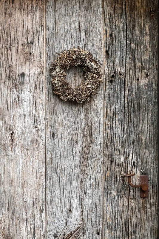 Very old weathered wooden door with a wreath of twigs and lichen