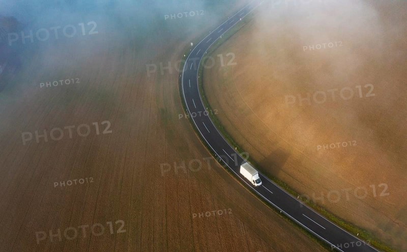 Drone view of a rural landscape shrouded in dense morning fog with a country road near Prambachkirchen