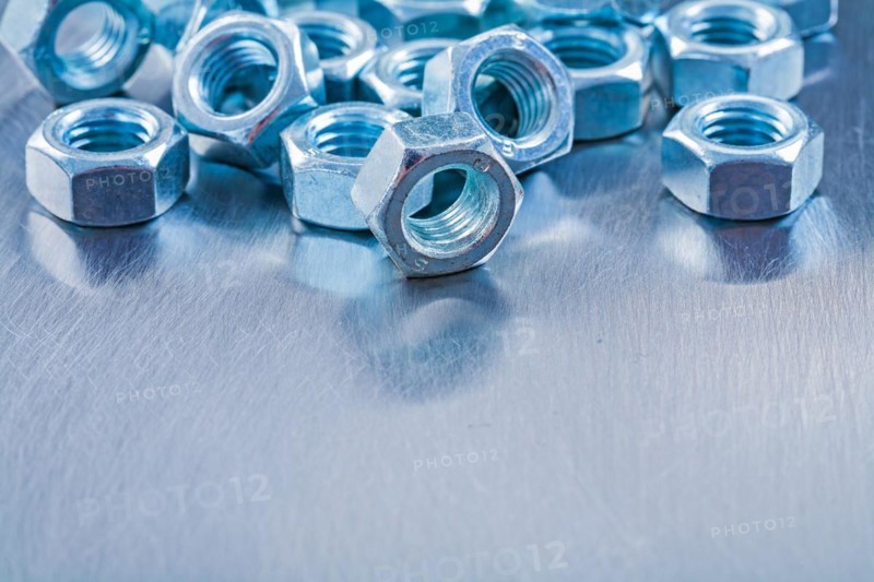 Large set of stainless steel nuts on metallic background Construction concept