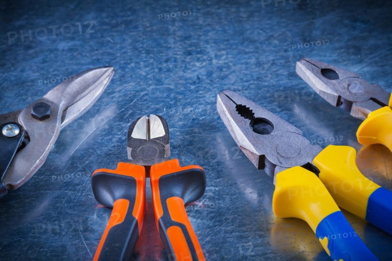 Tin snips pliers pliers on scratched vintage metallic surface horizontal version construction concept