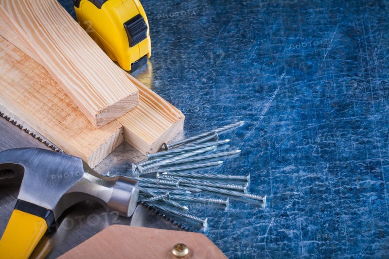 Composition of metal nails Hammer Wooden bricks Hacksaw Tape measure on scratched metal surface Construction concept