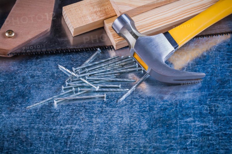 Close up image of metal nails hammer wooden bricks hacksaw on scratched metallic surface construction concept
