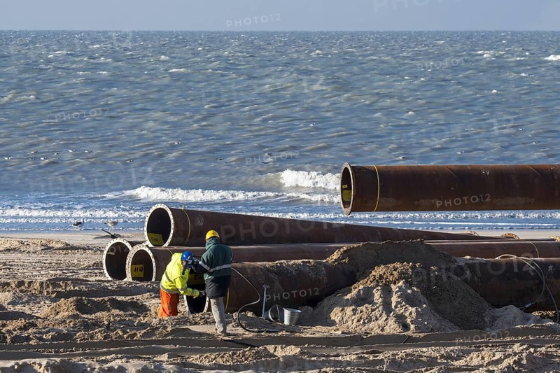 Dredging workers connecting pipes of pipeline during sand replenishment