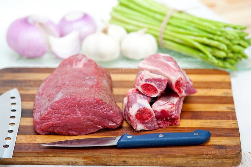 Raw beef and pork ribs with asparagus and herbs ready to cook