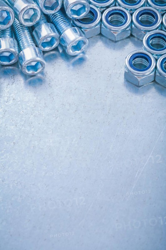 Copy space image of threaded stainless bolts and nuts on metallic background construction concept
