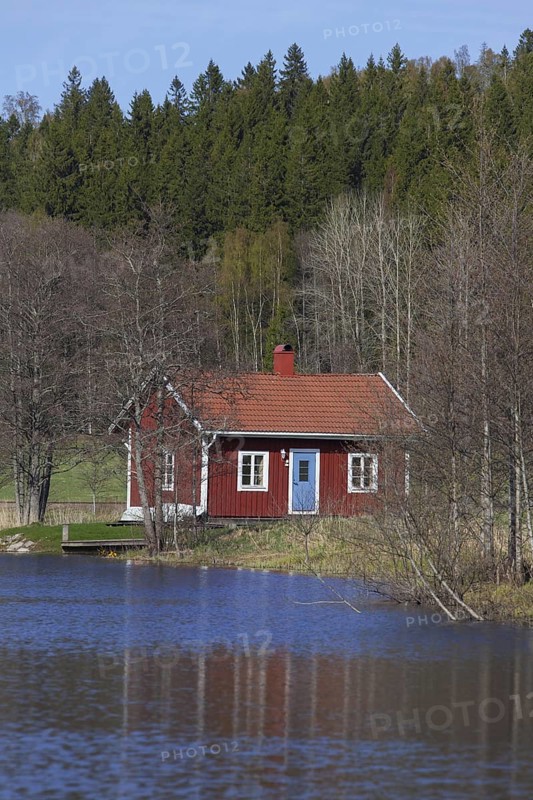 Swedish red wooden cabin along river in spring