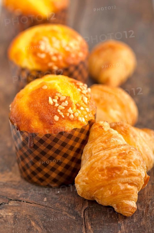 Fresh baked muffin and croissant mignon on old wood table