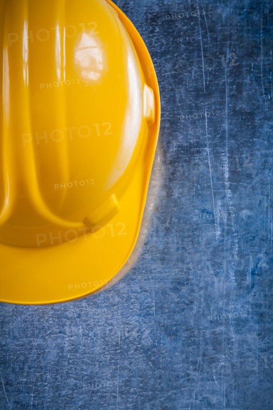 Hard hat on scratched vintage metallic background construction concept