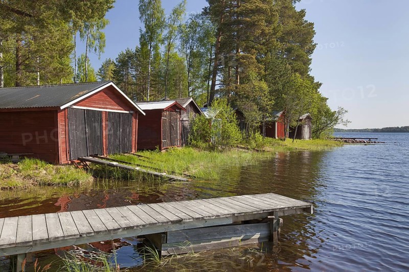 Red wooden boathouses along lake Siljan in summer