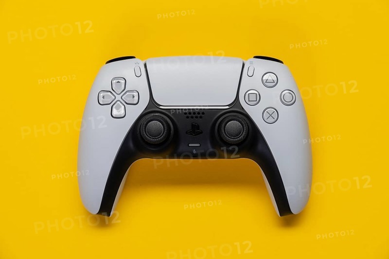 Controller of the PS5 Playstation game console from Sony in front of a monochrome yellow background