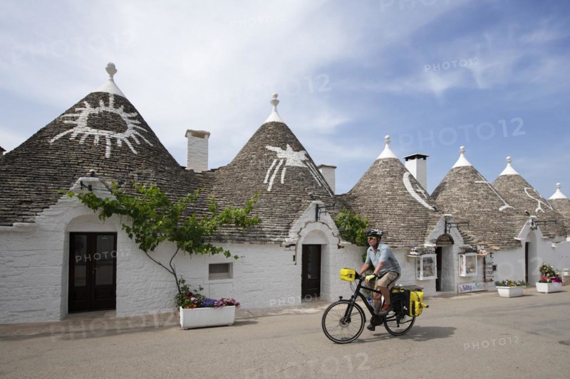 Cyclist between trulli in Alberobello