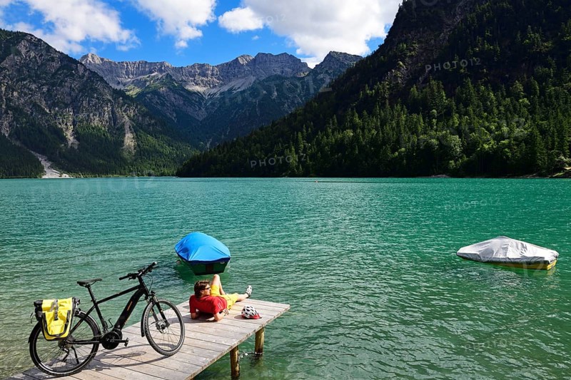 Cyclist taking a break on a wooden footbridge at Plansee