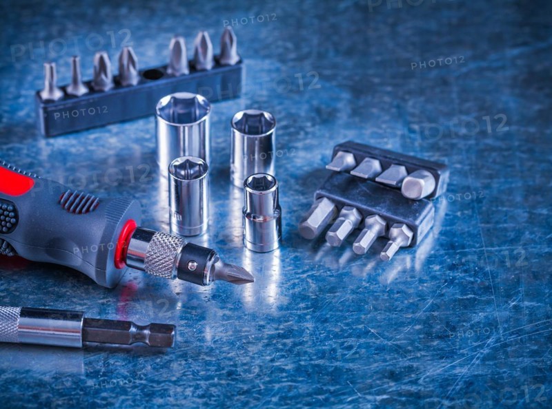 Tool set with screwdriver with stainless steel interchangeable bits and Torx on scratched metallic background Design concept