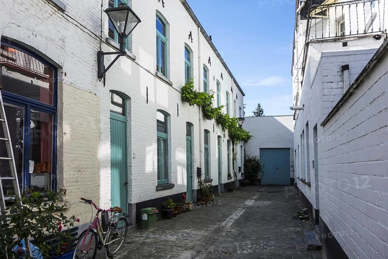 Old dead-end alley with white working-class houses in the city Aalst