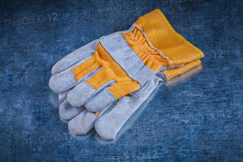 Pair of safety work gloves on scratched vintage metallic background close up image construction concept