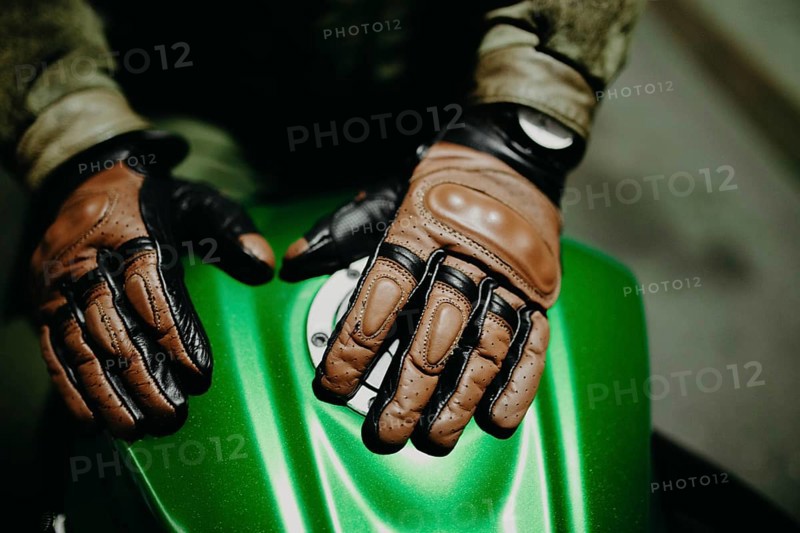 A motorcyclist shows his leather brown gloves for a touring trip to the camera