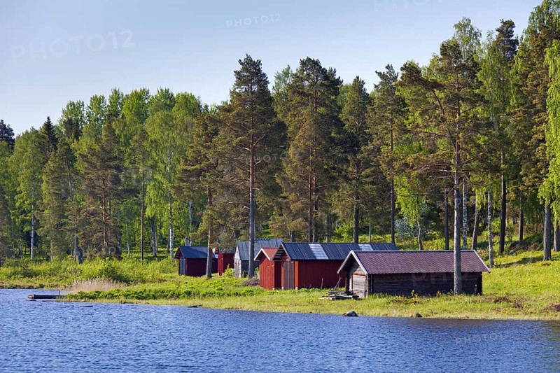Red wooden boathouses along lake Siljan in summer