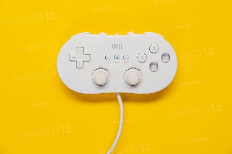 Classic game controller Nintendo Wii game console in front of plain yellow background