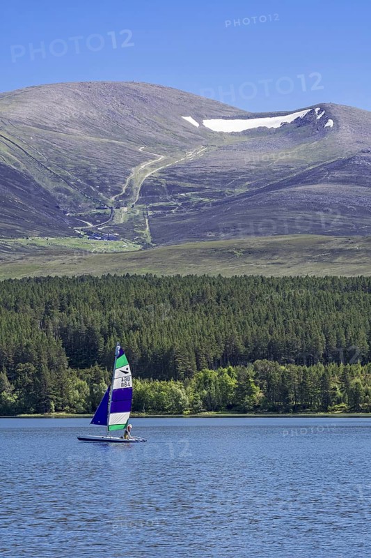 Sailing boat on Loch Morlich in front of the Cairngorm Mountains