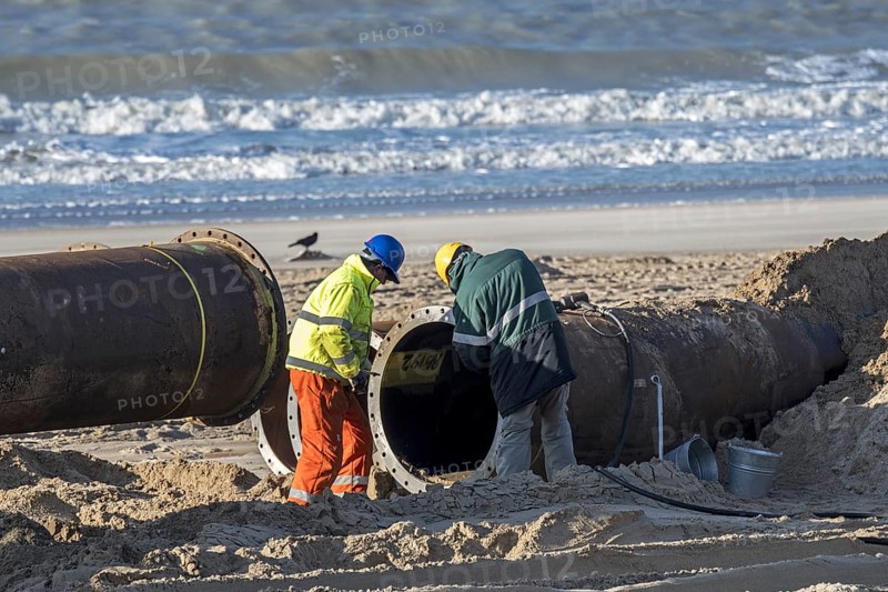 Dredging workers connecting pipes of pipeline during sand replenishment