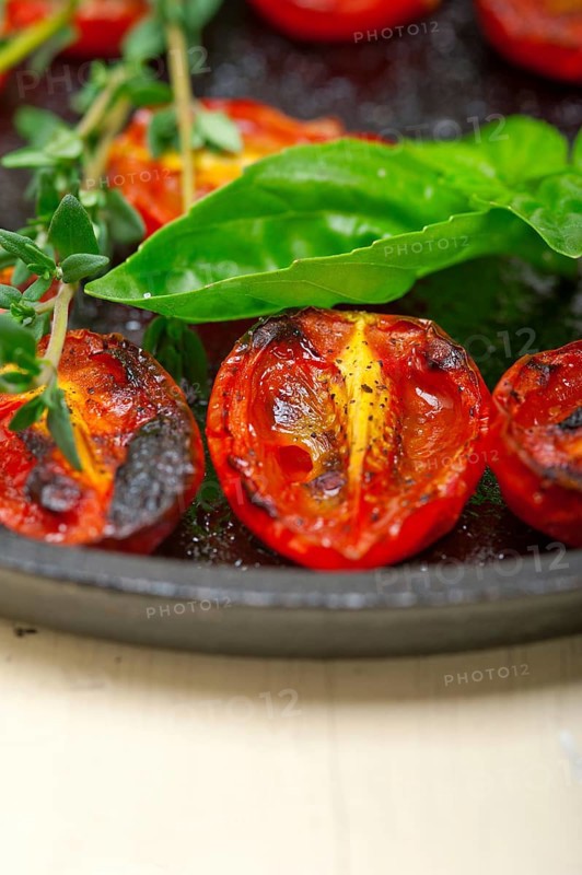 Oven baked cherry tomatoes with basil and thyme on a cast iron skillet