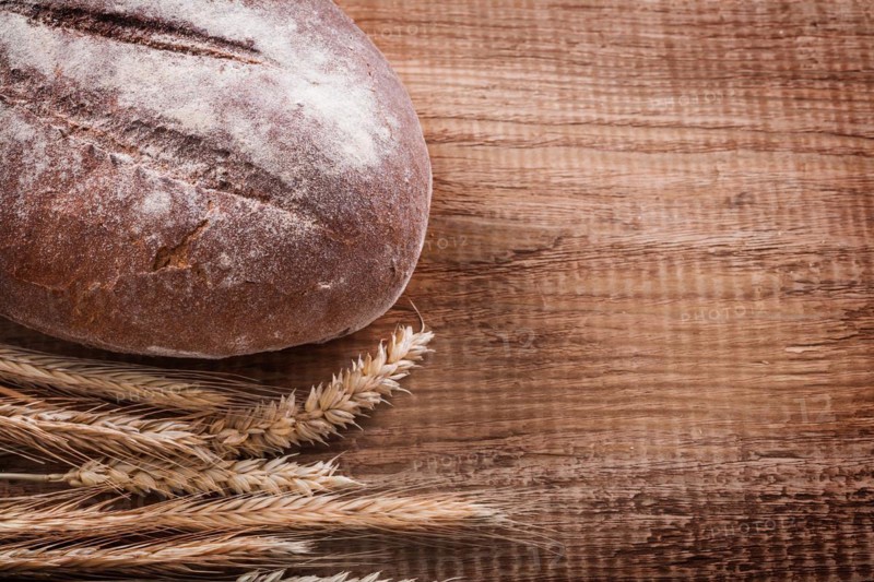 Bundle of wheat ears long loaf on oak wooden board Food and drink concept
