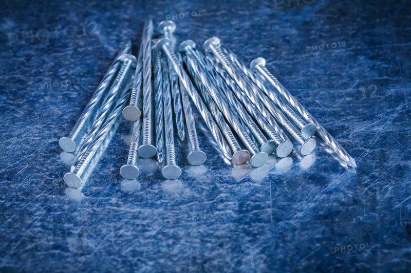 Pile of stainless steel nails on scratched metallic background Maintenance concept