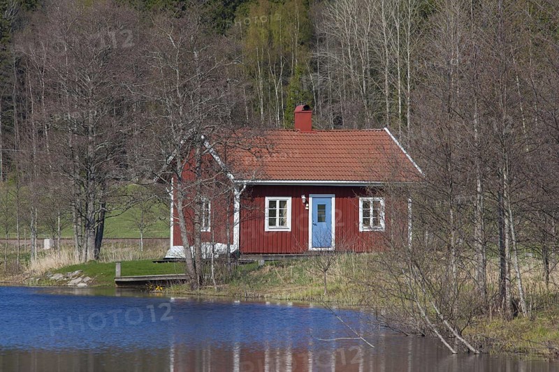 Swedish red wooden cabin along river in spring