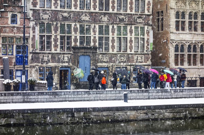 Guided tour with tourists visiting the city Ghent during snow shower in winter