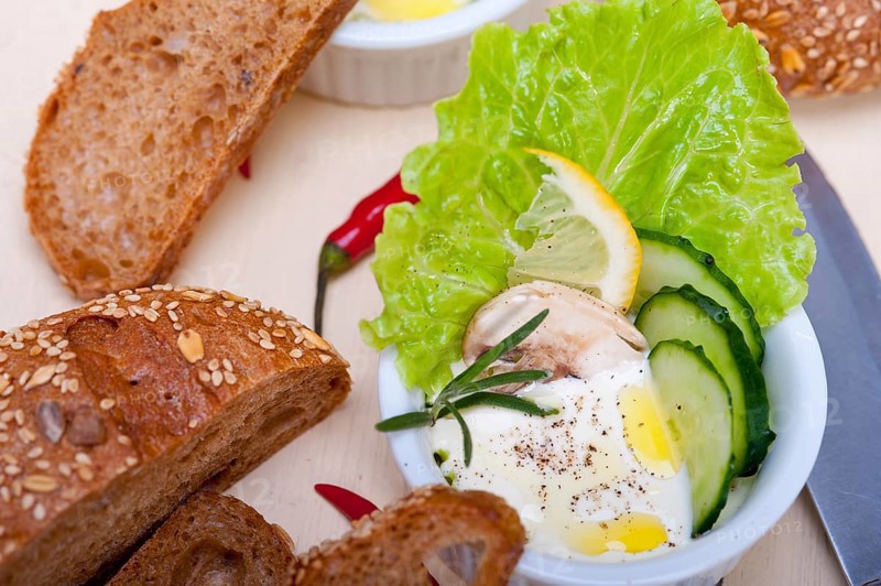 Fresh organic garlic cheese dip salad on a rustic table with bread