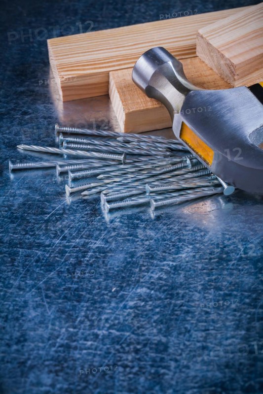 Metal nails claw hammer and wooden bolt on scratched metallic background copy space image construction concept